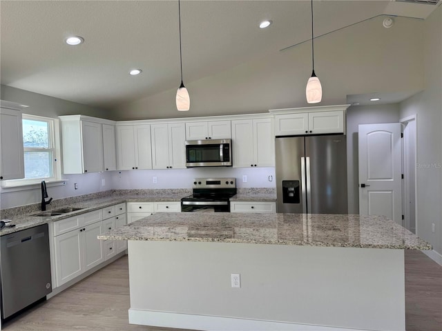 kitchen with appliances with stainless steel finishes, pendant lighting, white cabinetry, and sink