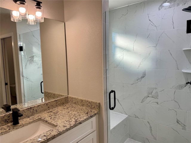 bathroom featuring a shower with door and vanity