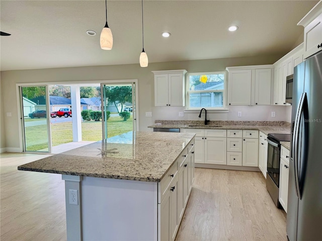 kitchen with stainless steel appliances, sink, white cabinets, and a center island