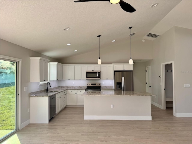 kitchen featuring light hardwood / wood-style floors, a kitchen island, white cabinetry, hanging light fixtures, and stainless steel appliances