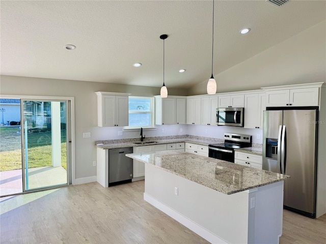 kitchen featuring white cabinets, appliances with stainless steel finishes, a center island, sink, and hanging light fixtures