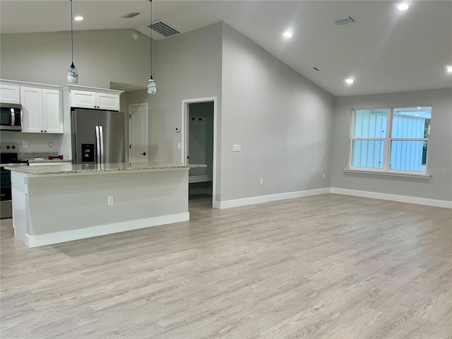 kitchen with appliances with stainless steel finishes, white cabinetry, hanging light fixtures, and a kitchen island