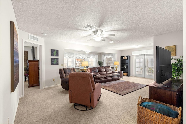 carpeted living room with french doors, ceiling fan, plenty of natural light, and a textured ceiling