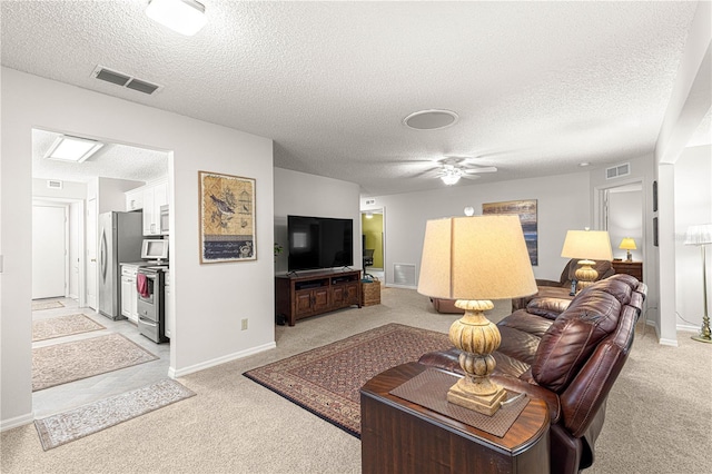 living room with light carpet, ceiling fan, and a textured ceiling