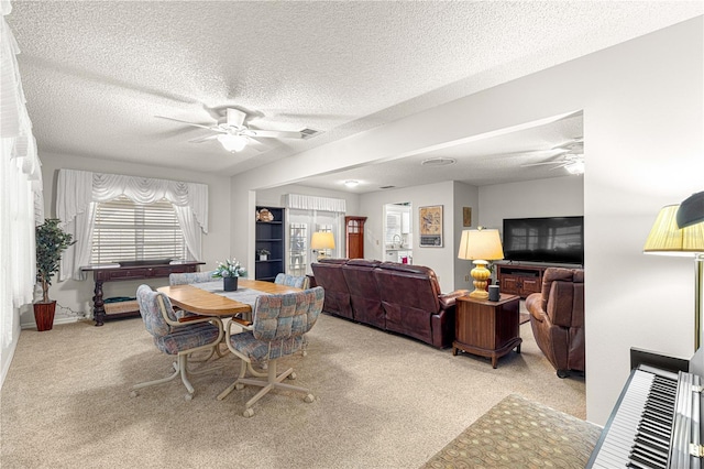 dining space with a textured ceiling, ceiling fan, and light carpet