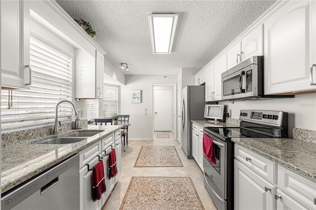 kitchen featuring light stone countertops, white cabinetry, sink, and stainless steel appliances