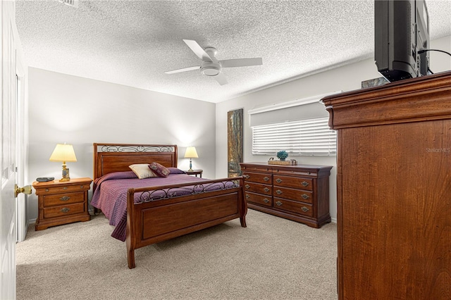 bedroom with ceiling fan, light colored carpet, and a textured ceiling