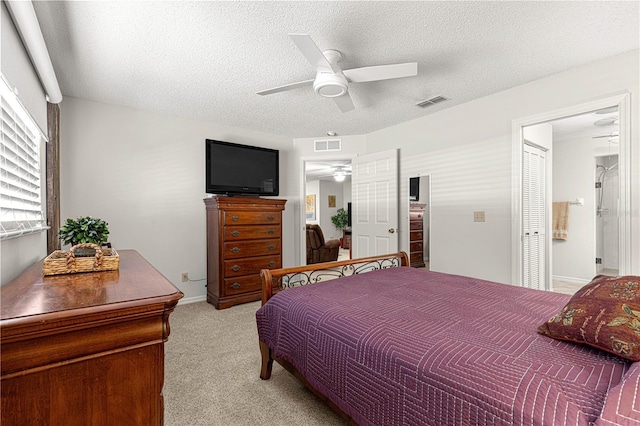 bedroom with a textured ceiling, ceiling fan, light carpet, and a closet