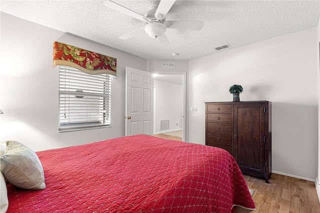 bedroom featuring light wood-type flooring, a textured ceiling, and ceiling fan