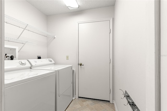 clothes washing area with washing machine and clothes dryer and a textured ceiling