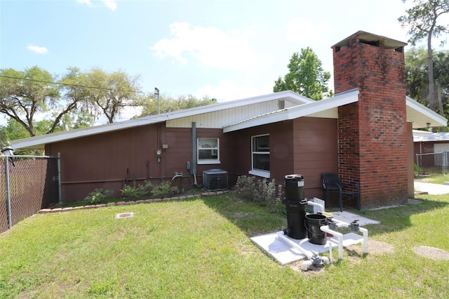 rear view of house featuring cooling unit and a yard