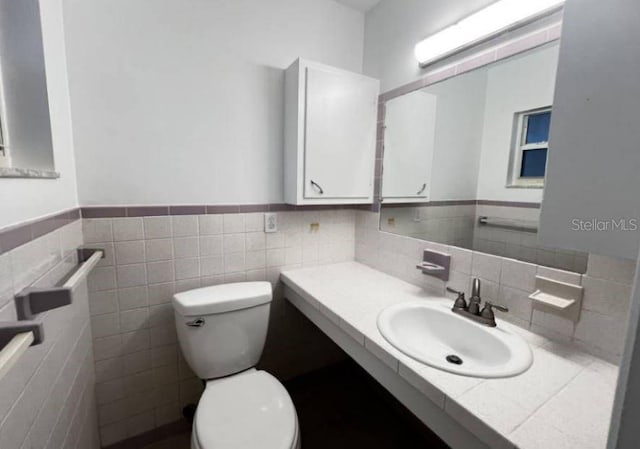 bathroom featuring vanity, toilet, and tile walls