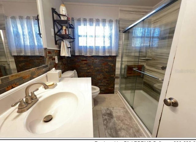 bathroom with tile patterned flooring, vanity, toilet, and a shower with door