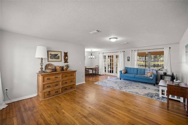 living room with hardwood / wood-style floors, a chandelier, and a textured ceiling