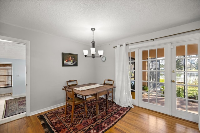 dining space featuring a chandelier, wood-type flooring, and a textured ceiling