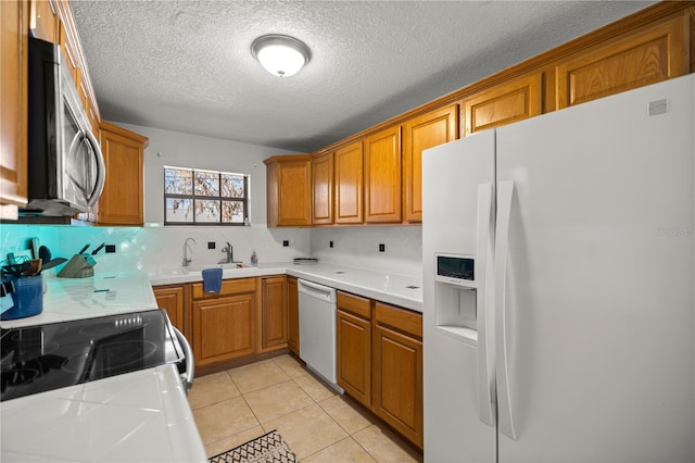 kitchen with sink, a textured ceiling, white appliances, decorative backsplash, and light tile patterned floors