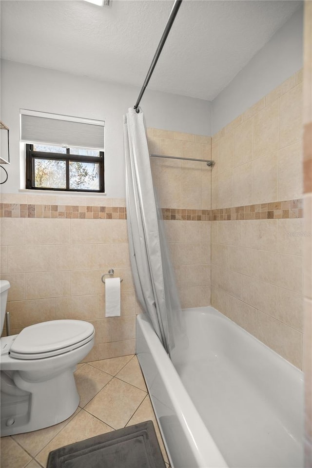 bathroom with shower / bathtub combination with curtain, tile patterned floors, a textured ceiling, toilet, and tile walls