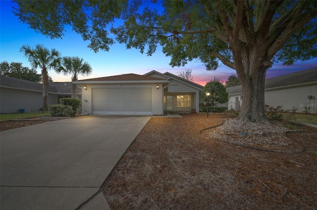 ranch-style house featuring driveway, brick siding, and an attached garage