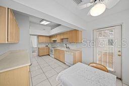 kitchen featuring ceiling fan, sink, light brown cabinets, range, and light tile patterned flooring