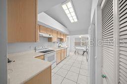 kitchen featuring electric range, light tile patterned flooring, and vaulted ceiling