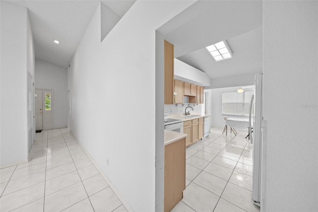 kitchen with sink, white appliances, lofted ceiling, and light tile patterned flooring