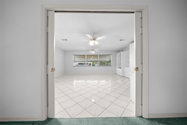 unfurnished room featuring light tile patterned floors, baseboards, a textured ceiling, and a ceiling fan