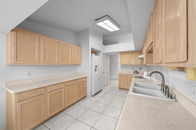 kitchen with light brown cabinets, a sink, white fridge with ice dispenser, light countertops, and light tile patterned floors