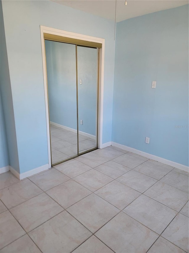 unfurnished bedroom with light tile patterned floors and a closet