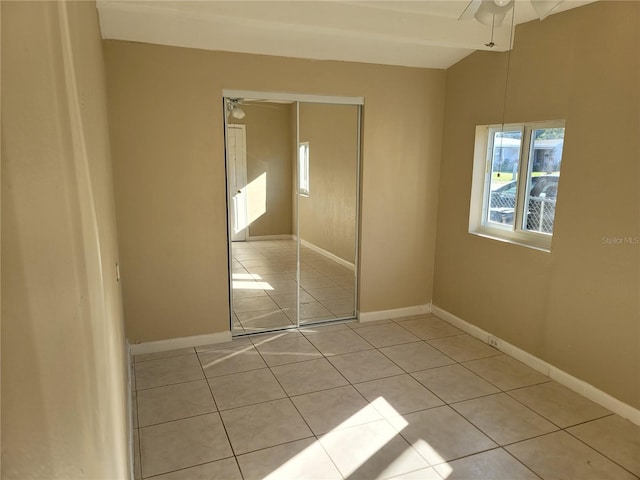 unfurnished bedroom with ceiling fan, light tile patterned flooring, and a closet