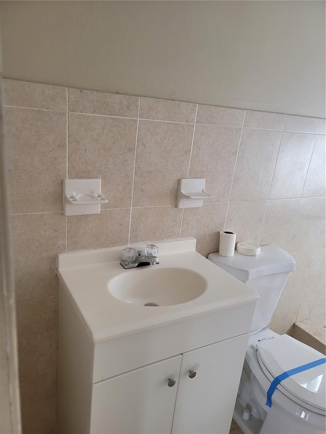 bathroom featuring vanity, toilet, and tile walls