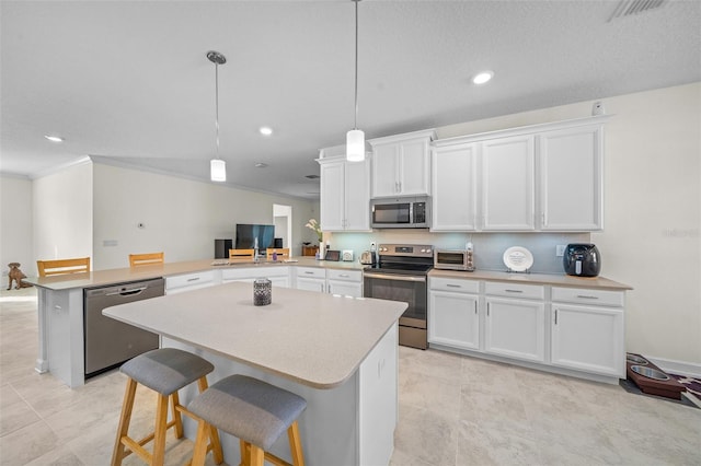 kitchen with kitchen peninsula, decorative light fixtures, stainless steel appliances, and white cabinetry