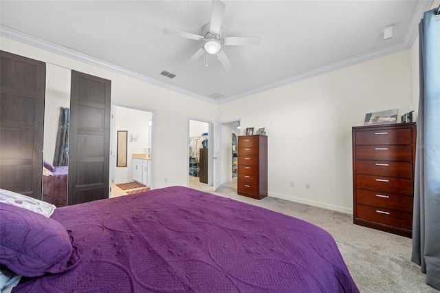 carpeted bedroom with a spacious closet, ceiling fan, ornamental molding, and ensuite bathroom