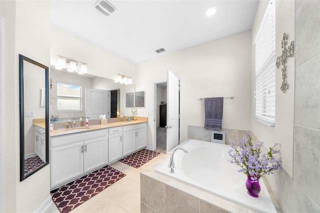 bathroom with tiled tub, tile patterned flooring, and vanity