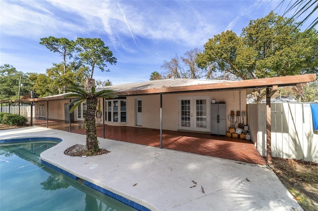 rear view of house with a patio area, a fenced in pool, and french doors