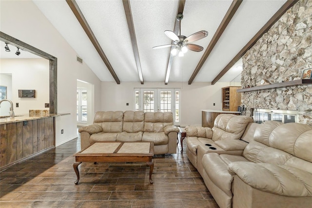 living room with a textured ceiling, vaulted ceiling with beams, ceiling fan, and sink