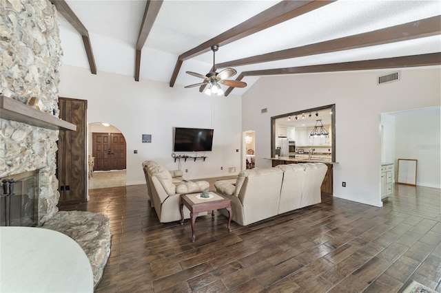 living room featuring beam ceiling, ceiling fan, a fireplace, and high vaulted ceiling