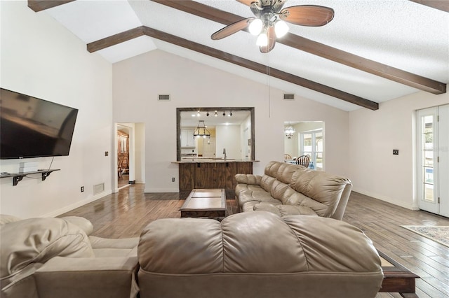 living room with hardwood / wood-style floors, ceiling fan with notable chandelier, a textured ceiling, and high vaulted ceiling