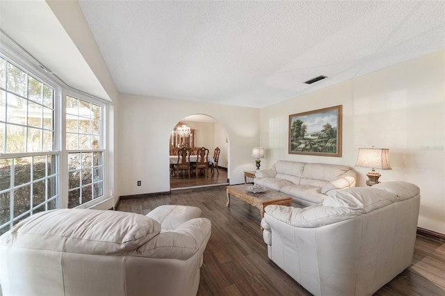 living room with a textured ceiling, an inviting chandelier, and dark wood-type flooring