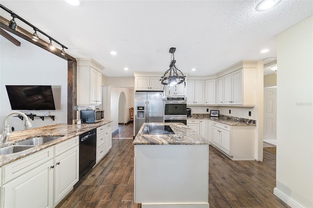 kitchen with light stone counters, sink, black appliances, pendant lighting, and white cabinetry