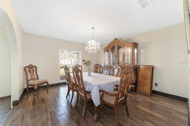 dining room with a textured ceiling, dark hardwood / wood-style flooring, and an inviting chandelier