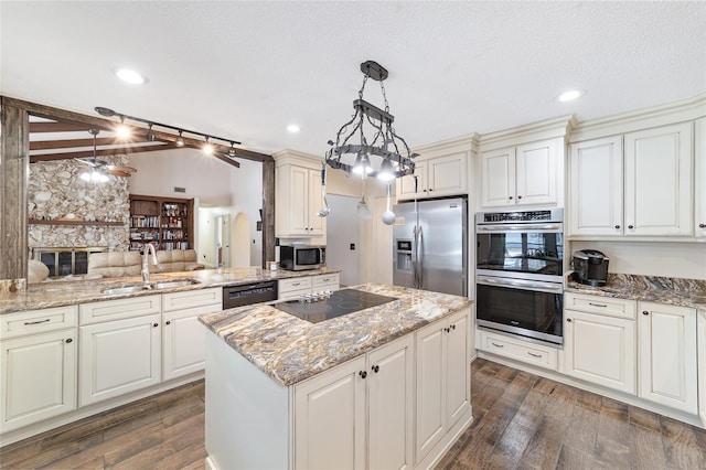 kitchen featuring dark wood-type flooring, sink, black appliances, pendant lighting, and a center island