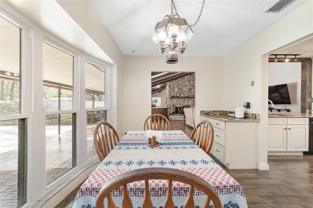 dining area featuring a fireplace, a textured ceiling, dark hardwood / wood-style flooring, and a notable chandelier