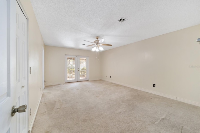 carpeted empty room with ceiling fan, french doors, and a textured ceiling