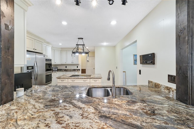 kitchen featuring kitchen peninsula, stainless steel fridge with ice dispenser, sink, and stone countertops