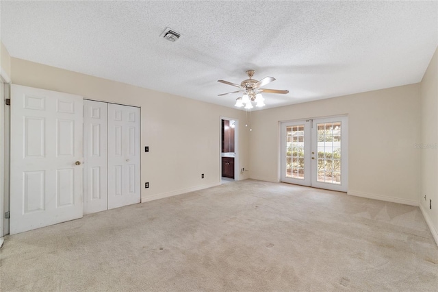 unfurnished room featuring light carpet, french doors, a textured ceiling, and ceiling fan