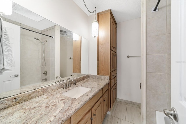 bathroom with a textured ceiling, vanity, tile patterned floors, and tiled shower / bath