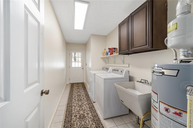 washroom featuring cabinets, sink, water heater, light tile patterned floors, and separate washer and dryer