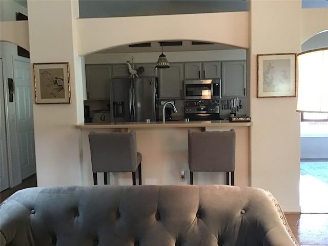 kitchen featuring black range with electric stovetop, sink, hanging light fixtures, gray cabinets, and fridge with ice dispenser