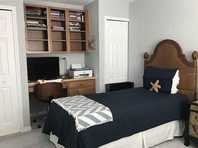 bedroom with built in desk and light colored carpet