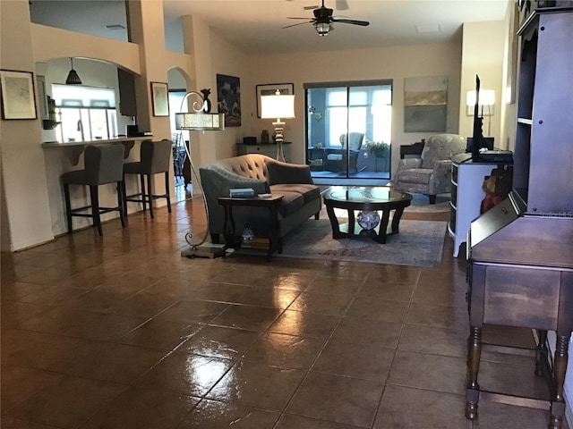 living room featuring dark tile patterned floors, arched walkways, and ceiling fan